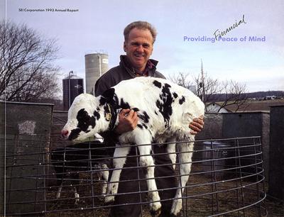 Annual Reports and Corporate Communications depicts: A smiling man holds up a baby cow in front of a farm