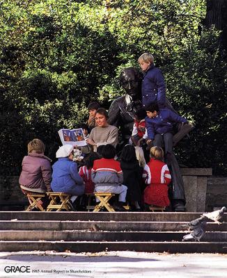 Annual Reports and Corporate Communications depicts: A teacher reads a picture book to a group of young children in a park. They sit on stools at the top of a small set of stairs 