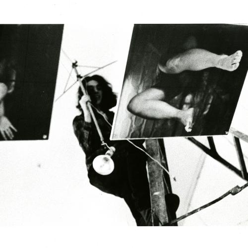 Photographic Materials depicts: Two photos with legs; artist is standing above photos
