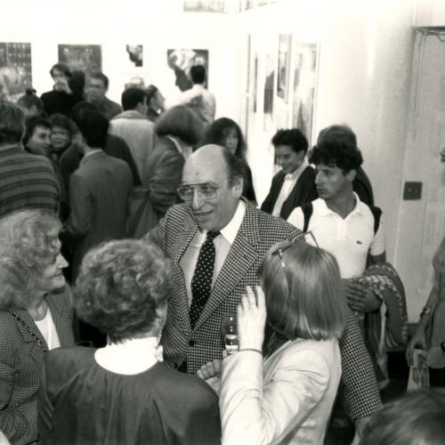 Photographic Materials, Digital Files depicts: opening reception photo, Glaser speaking to others in a crowd