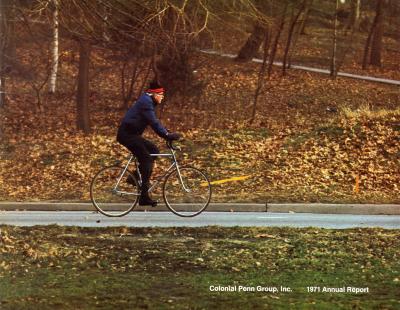 Annual Reports and Corporate Communications depicts: A man rides a bike through a fall landscape 