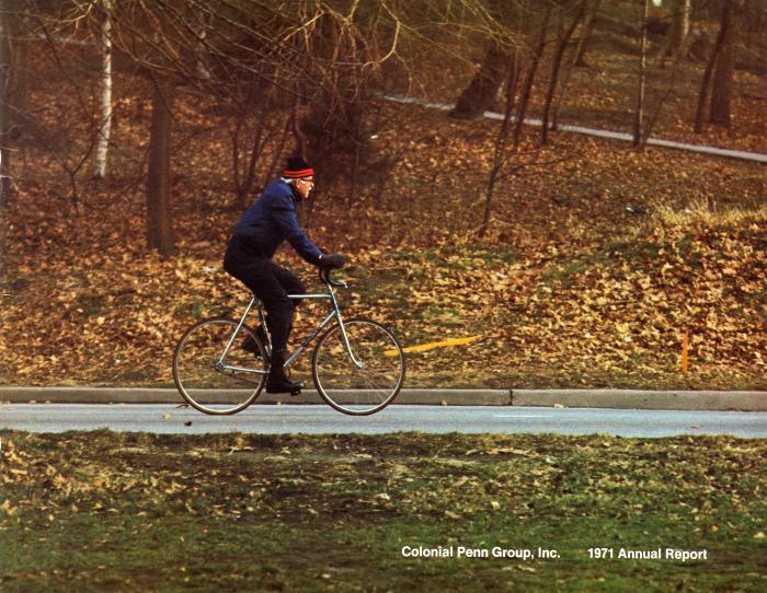 Annual Reports and Corporate Communications depicts: A man rides a bike through a fall landscape 