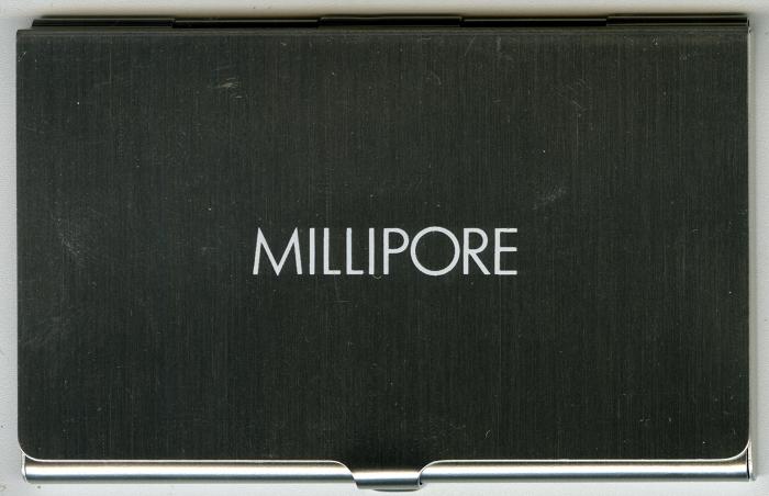 Three-Dimensional Objects, Logos and identities depicts: A metal business card holder with "Millipore" engraved on the front