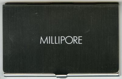 Three-Dimensional Objects, Logos and identities depicts: A metal business card holder with "Millipore" engraved on the front