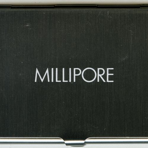 Three-Dimensional Objects, Logos and identities depicts: A metal business card holder with "Millipore" engraved on the front