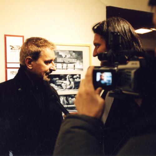 Photographic Materials depicts: Featured artist filmed by man with home video recorder