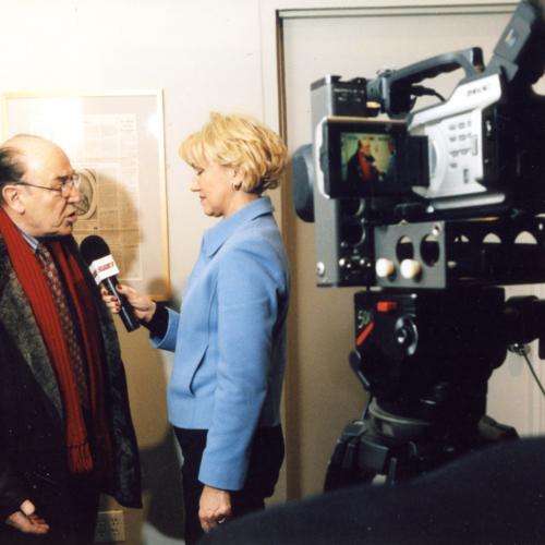 Photographic Materials depicts: featured artists being interviewed by woman, filmed by cameraman