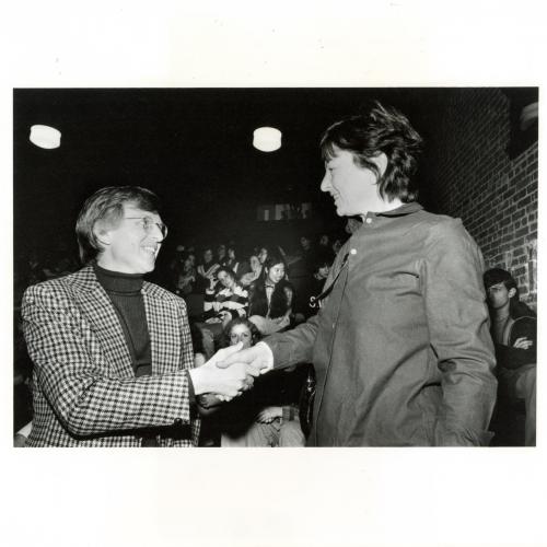 Photographic Materials depicts: black and white photo of Elderfield shaking hands with Jeanne Siegel with audience in background
