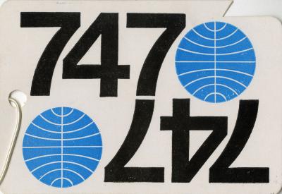 White luggage tag with the numbers "737" written in black and a blue circle with white lines running through it. Its mirror image is on the bottom side of the luggage tag such that when the tag is flipped it reads the same way.