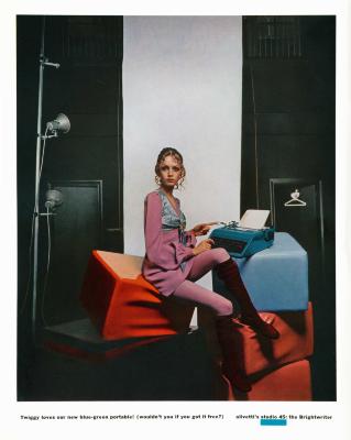Advertisements depicts: Twiggy sits on an orange block and types on a blue typewriter which is sitting on a pile of blue and orange blocks