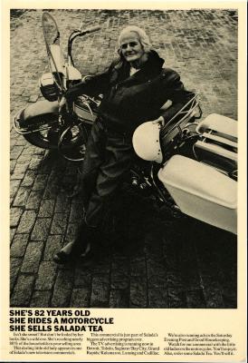 Advertisements depicts: Old woman waring leather leaning against a white motorcycle 