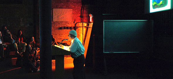 Tony, in profile, makes comments on his work during an intimate slide show.