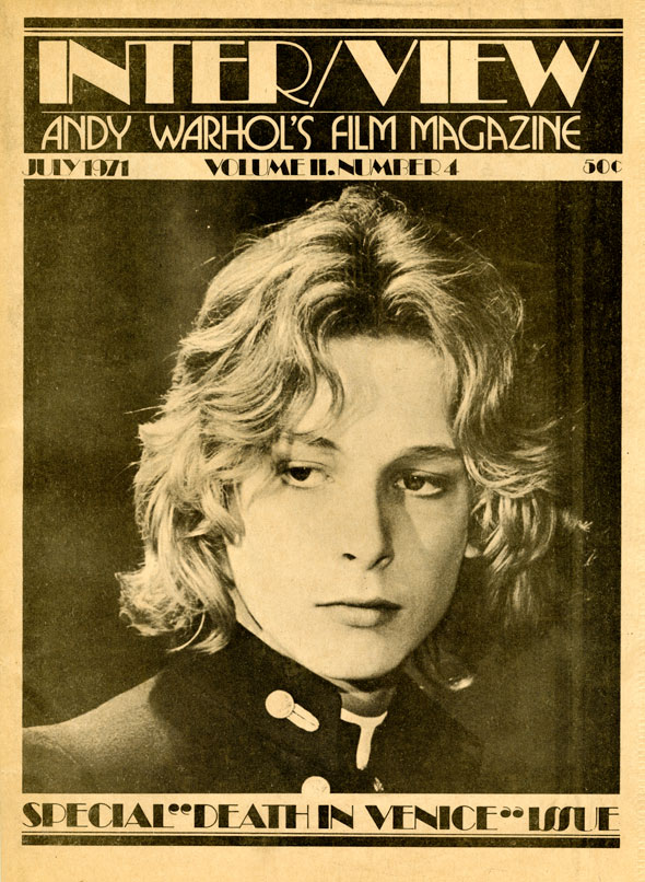 Black and white photo of an androgynous person with light wavy hair looking off-camera