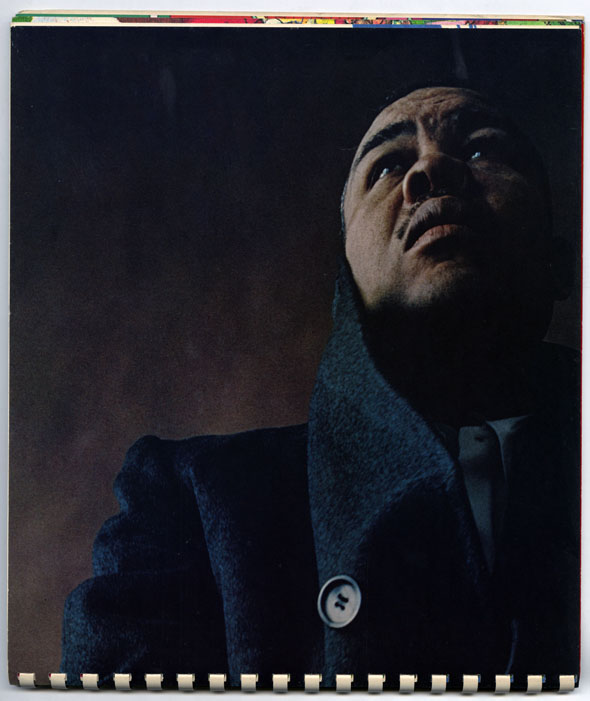 Dark color photo of a man in a heavy coat looking up