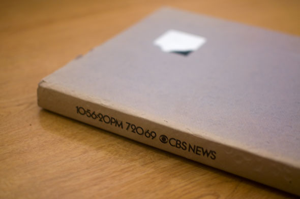 Color photo of a grey book on a table. Spine reads 10:56:20PM 72069 CBS News